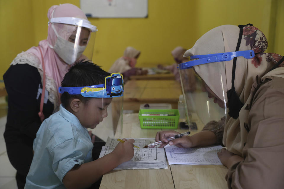 Teachers and students wear protective gear as a precaution against the new coronavirus outbreak during a class at a Quran educational facility at on the outskirts of Jakarta, Indonesia, Wednesday, July 1, 2020. The government of Indonesia's capital region is extending the first transition phase from large-scale social restrictions in Jakarta as the number of new confirmed coronavirus cases continues to rise. (AP Photo/Tatan Syuflana)