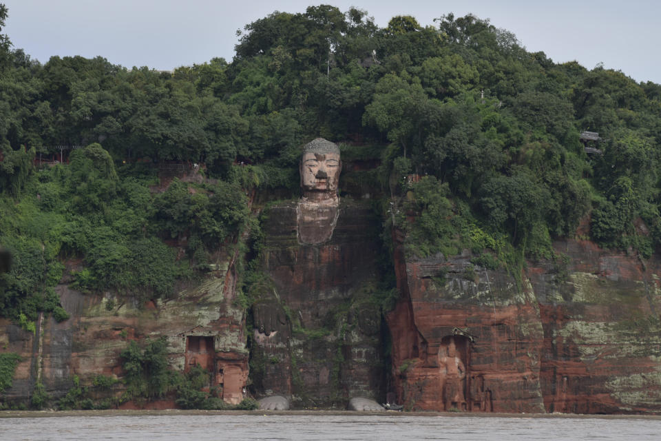 In this photo released by China's Xinhua News Agency, floodwaters flow near the historic Giant Buddha in Leshan in southwestern China's Sichuan Province on Aug. 18, 2020. China faced a double whammy Wednesday of flooding and landslides from unusually heavy seasonal rains and a typhoon that came ashore on its southern coast. (Xu Bingjie/Xinhua via AP)