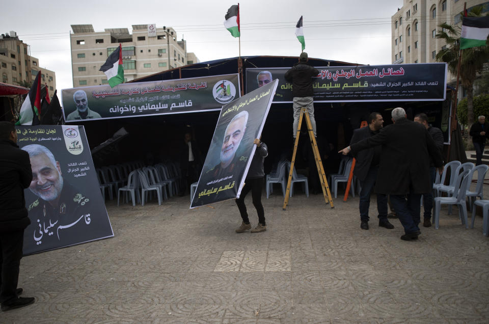 Palestinian man carries a poster of Qassem Soleimani, the Iran's head of the Quds Force who was killed in a US drone strike early Friday, in front of a morning house held by Palestinian factions for Sleimani in Gaza City, Saturday, Jan 4, 2020. (AP Photo/Khalil Hamra)