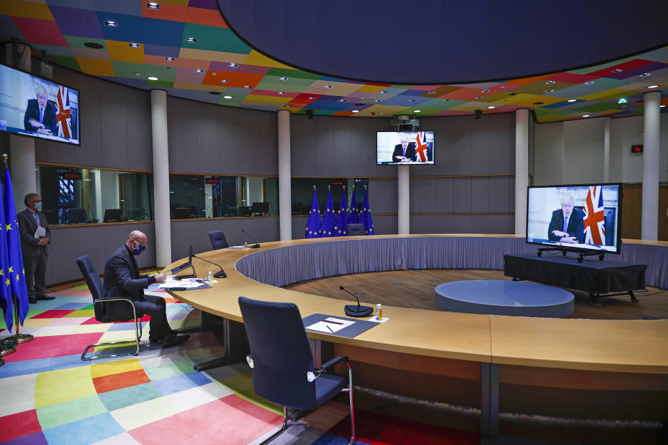 FILE - European Council President Charles Michel, left, reviews his notes as he listens to British Prime Minister Boris Johnson, displayed on screens, during the One Planet Summit 2021 video conference at the European Council headquarters in Brussels, Jan. 11, 2021. Outgoing U.K. Prime Minister Boris Johnson has been the bane of Brussels for many years, from his days stoking anti-European Union sentiment with exaggerated newspaper stories to his populist campaign leading Britain out of the bloc and reneging on the post-Brexit trade deal he himself signed. (AP Photo/Francisco Seco, file)