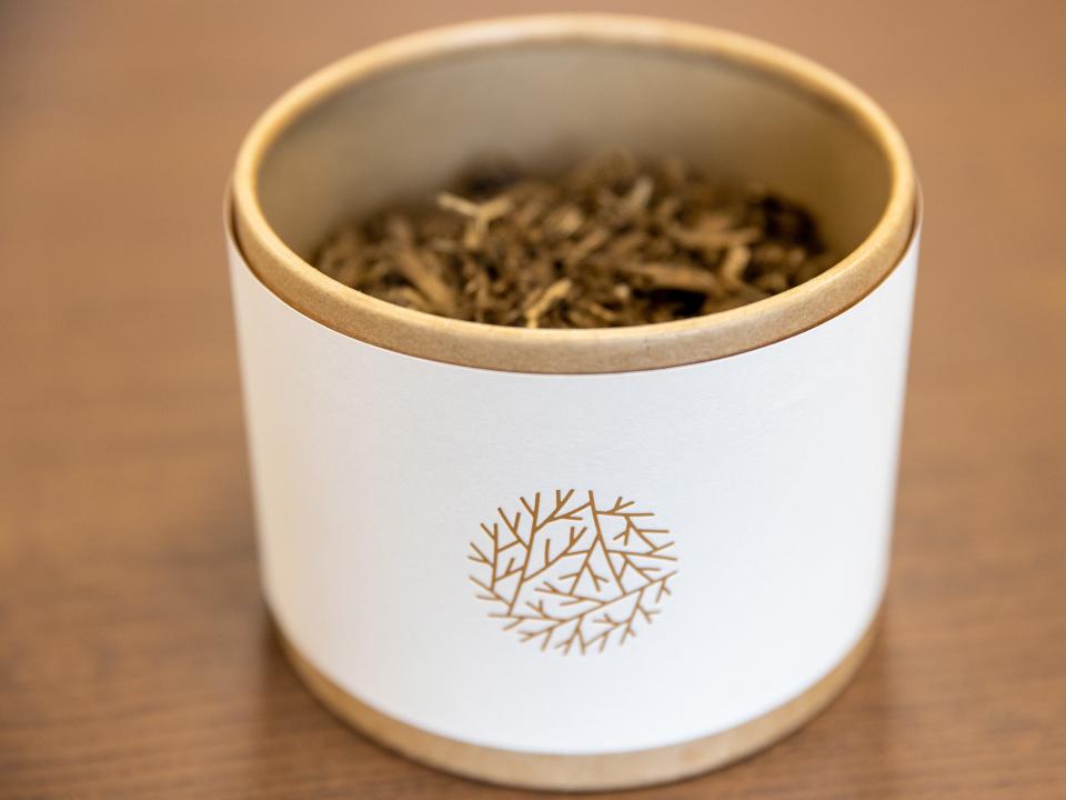 A small plant pot with the logo of Recompose is shown two-thirds full of soil .