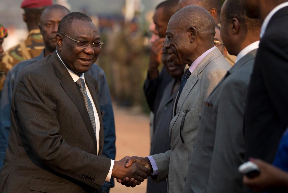 Central African Republic President Michel Djotodia, left, shakes hands with assembled dignitaries as he departs for Chad, at Mpoko Airport in Bangui, Central African Republic, Wednesday, Jan. 8, 2014. The embattled president, who has come under growing pressure to resign, traveled to neighboring Chad on Wednesday for a summit with regional leaders who want to end the bloodshed that has left more than 1,000 dead and nearly a million people displaced. (AP Photo/Rebecca Blackwell)