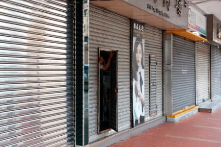 An employee peeks from a closed store following a violent attack on residents happened at Yuen Long, in Hong Kong