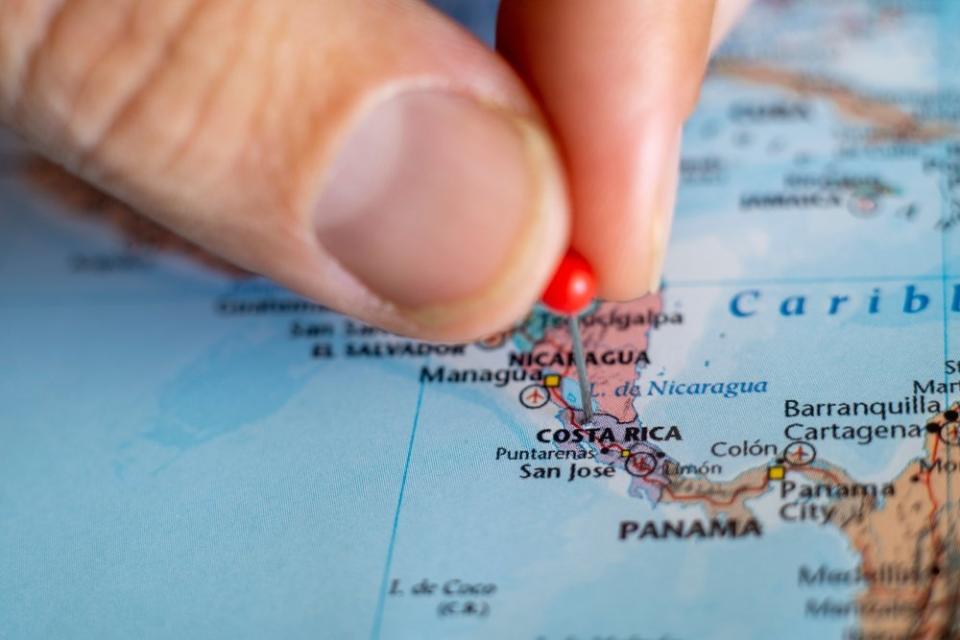 person holding a tack on a map of the Costa Rica Panama border 