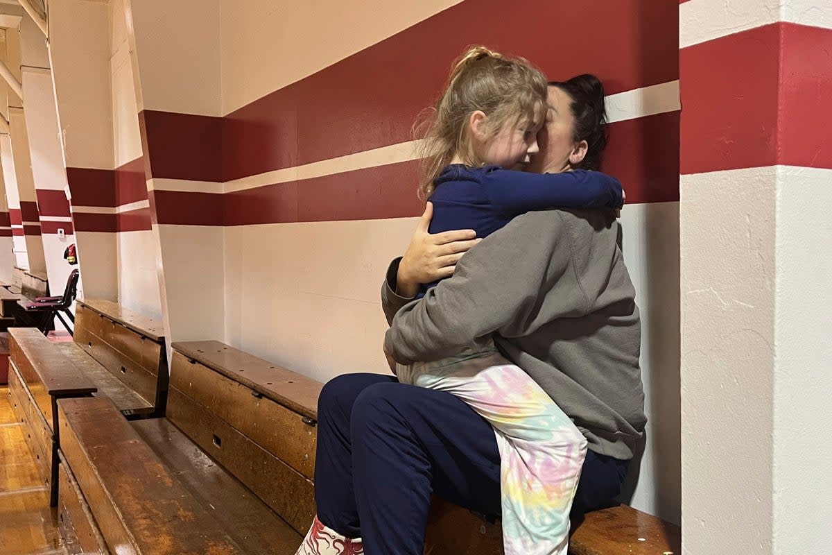 Angela Stires is embraced by her daughter, Tuesday, 21 November 2023, at the community center, which opened for people displaced by the landslide in Wrangell, Alaska (AP)