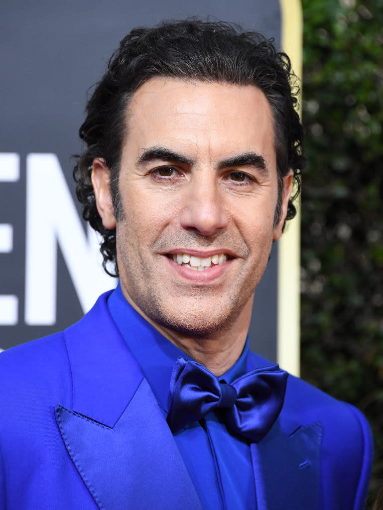 Sacha Baron Cohen in a tux smiling at an event