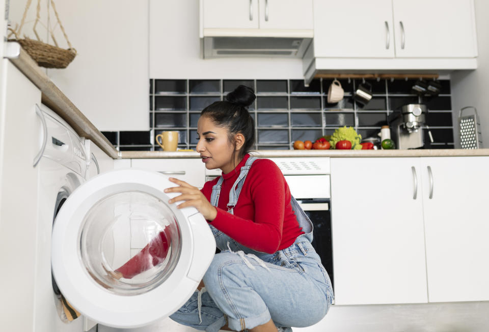 Woman removing clothes from tumble drier