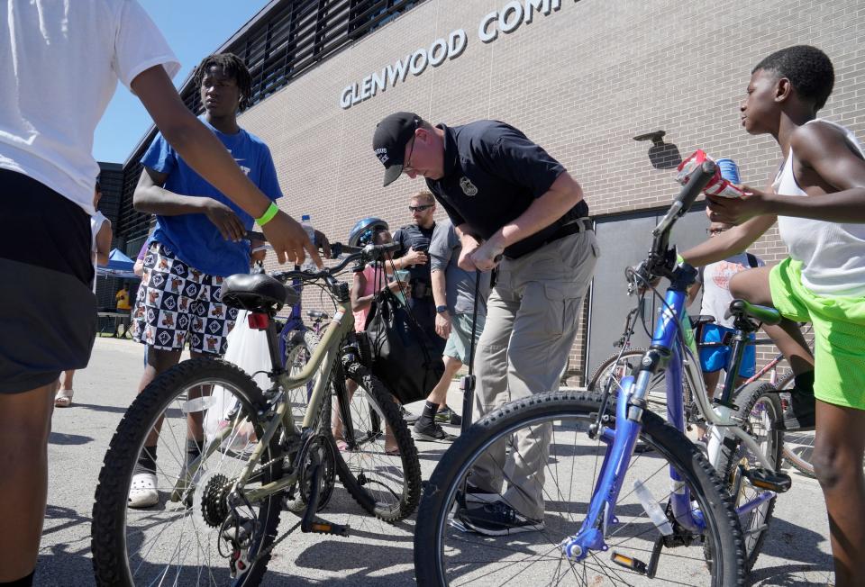 June 23, 2022; Columbus, Ohio, USA; Columbus police officers Jon Johnson, puts air in tires during a Bikes & Badges event at Glenwood Community Center on Thursday. Mandatory Credit: Barbara Perenic/Columbus Dispatch