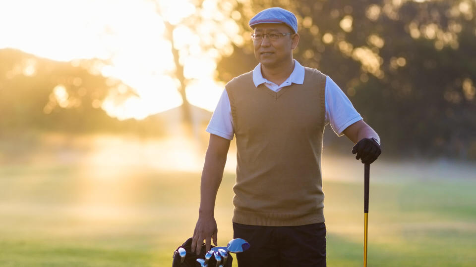 Full length of mature man standing at golf course.