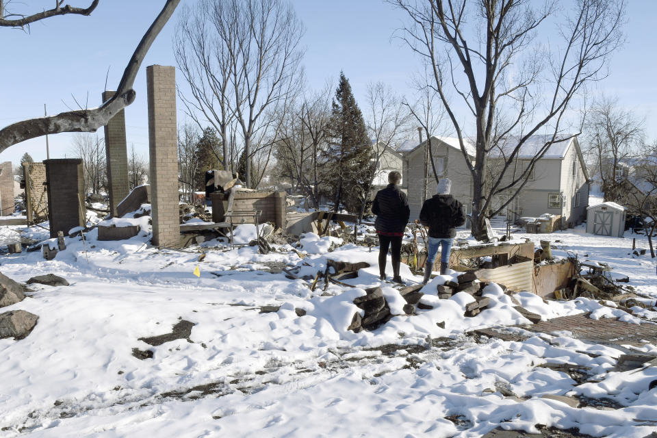 FILE - Barba Hickman, left, surveys her destroyed home in Louisville, Colo., with her daughter-in-law, Austen Hickman, Jan. 2, 2022. Some homeowners recovering from Colorado's most destructive wildfire in history, which decimated entire neighborhoods near Denver late last year, say they could end up paying tens of thousands of dollars more to rebuild because of environmentally sustainable construction standards passed shortly before the blaze. (AP Photo/Thomas Peipert, File)