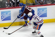 Colorado Avalanche right wing Brandon Duhaime, back, slips the puck past Edmonton Oilers center Ryan McLeod during the first period of an NHL hockey game Thursday, April 18, 2024, in Denver. (AP Photo/David Zalubowski)