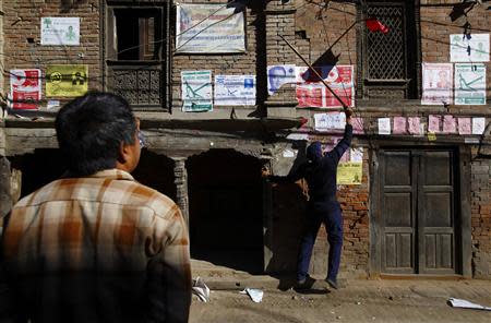 A police personnel recruited for the Constituent Assembly election, removes a party flag near the polling station a day before the election in Bhaktapur November 18, 2013. REUTERS/Navesh Chitrakar