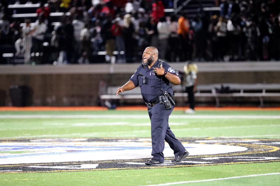A Savannah Police Officer runs across the field after a fight broke out on the Jenkins side of Memorial Stadium on Firday, August 18, 2023.