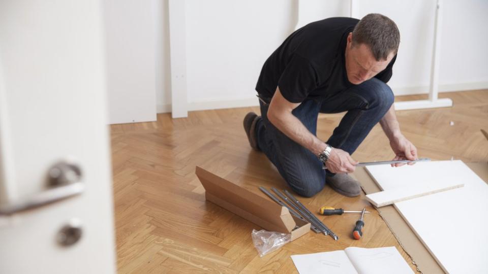 Hombre leyendo instrucciones para armar un mueble