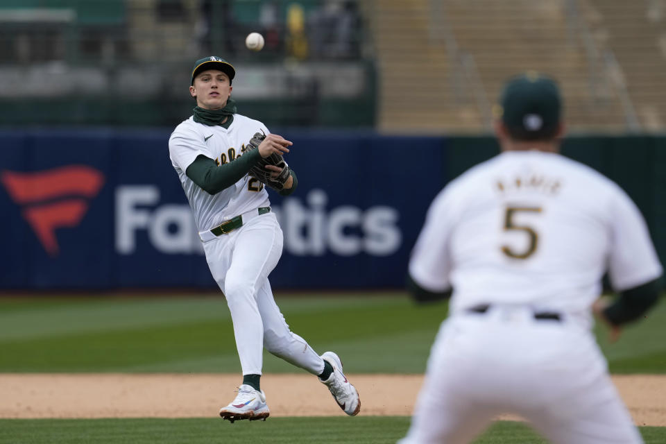 Oakland Athletics second baseman Zack Gelof, left, throws to first baseman J.D. Davis, foreground, for the out on Washington Nationals' Trey Lipscomb during the sixth inning of a baseball game Saturday, April 13, 2024, in Oakland, Calif. (AP Photo/Godofredo A. Vásquez)