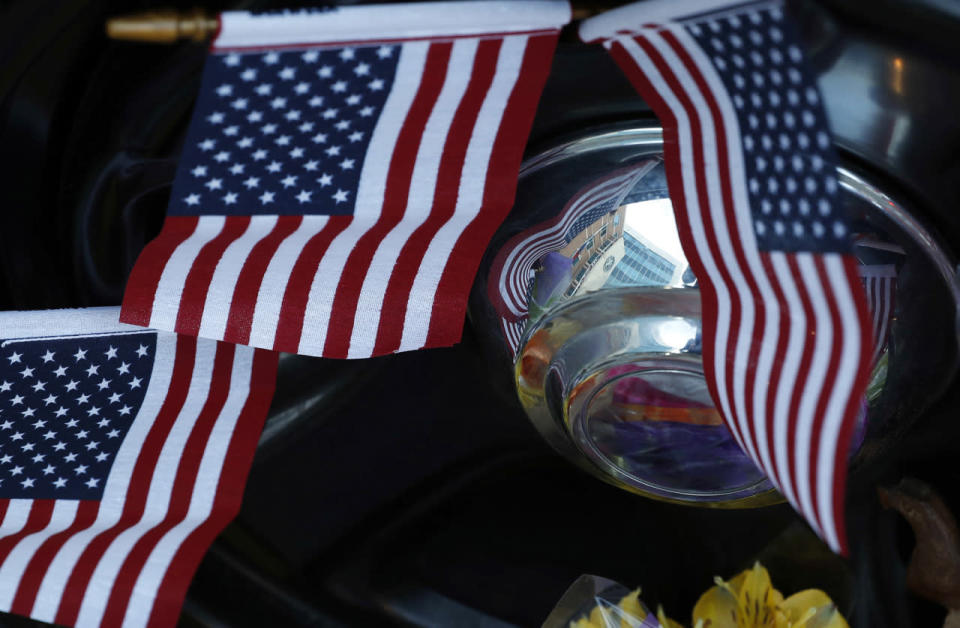 The Dallas Police Department headquarters building is reflected in the hubcap of a police car that is part of a makeshift memorial