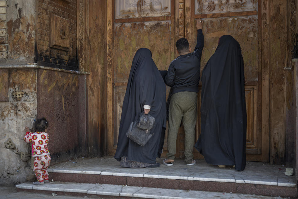 A man touches the door of the Office of the Martyr al-Sadr in Baghdad's Sadr City Friday, Feb. 24, 2023. This working-class, conservative and largely Shiite suburb in eastern Baghdad is home to more than 1.5 million people. (AP Photo/Jerome Delay)