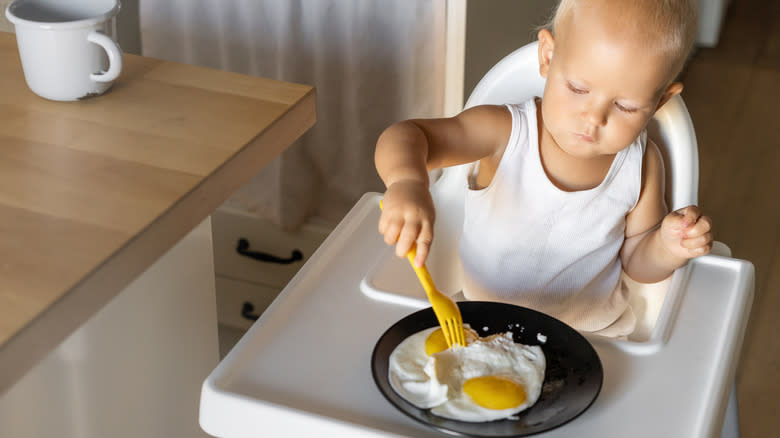 A toddler eating undercooked eggs