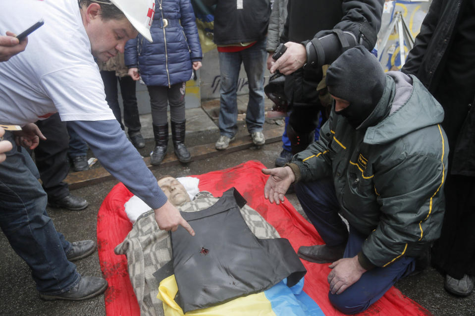 FILE - In this file photo taken on Thursday, Feb. 20, 2014, people look at a bullet hole in victim's vest who was killed during a clash between riot police and protesters in Independence Square, the epicenter of the country's current unrest in Kiev, Ukraine. Authorities in Ukraine said on Thursday that they have detained several members of an elite riot police unit on suspicion of shooting protesters during bloody anti-government clashes in February that left more than 100 dead. (AP Photo/Efrem Lukatsky, File)