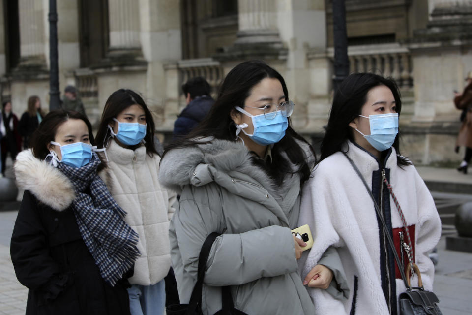 Tourists wearing a mask walks outside the Louvre museum Friday, Feb. 28, 2020 in Paris. . The world is scrambling to get on top of the new coronavirus outbreak that has spread from its epicenter in China to most corners of the planet. Governments and doctors are presenting an array of approaches as the virus disrupts daily routines, business plans and international travel around the world. (AP Photo/Rafael Yaghobzadeh)