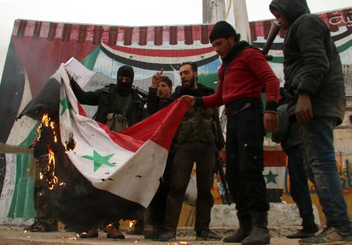 Fighters from a coalition of Islamist forces torch a Syrian flag after capturing the Syrian city of Idlib, on March 29, 2015 (AFP Photo/Zein al-Rifai)
