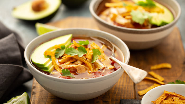 Taco soup topped with tortilla and avocado