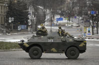 Ukrainian servicemen ride on top of an armored personnel carrier speeding down a deserted boulevard during an air raid alarm, in Kyiv, Ukraine, Tuesday, March 1, 2022. The U.N.'s refugees chief is warning that many more vulnerable people will begin fleeing their homes in Ukraine if Russia's military offensive continues and further urban areas are hit. (AP Photo/Vadim Ghirda)