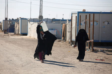 A displaced Iraqi woman carries a water container at the Amriyat al Fallujah camp in Anbar Province, Iraq January 3, 2018. Picture taken January 3, 2018. REUTERS/Khalid al-Mousily