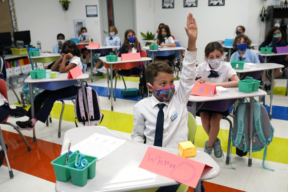 Student Winston Wallace, 9, raises his hand in class at iPrep Academy on the first day of school, Monday, Aug. 23, 2021, in Miami. Public schools in Miami-Dade County have a strict mask mandate to guard against coronavirus infections. A Florida judge ruled Wednesday, Sept. 8, that the state cannot enforce a ban on public schools mandating the use of masks to guard against the coronavirus, while an appeals court sorts out whether the ban is ultimately legal. (AP Photo/Lynne Sladky)