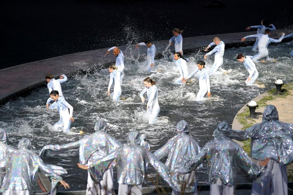 Performers dance on a water-soaked stage (Zac Goodwin/PA) (PA Wire)