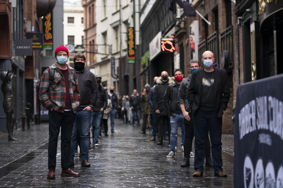 Members of the entertainment industry stand on Matthew Street in Liverpool, England, Monday Oct. 12, 2020, during a show of support for the hard hit sector as Prime Minister Boris Johnson lays out a new three-tier alert system for England. The British government is set to announce new restrictions on business and socializing in major northern England cities with high infection rates, under a plan to put areas into three tiers. (AP Photo/Jon Super)