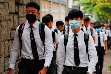 Some students from La Salle College wear masks, which have been banned at protests under emergency powers, as they walk to school in Hong Kong