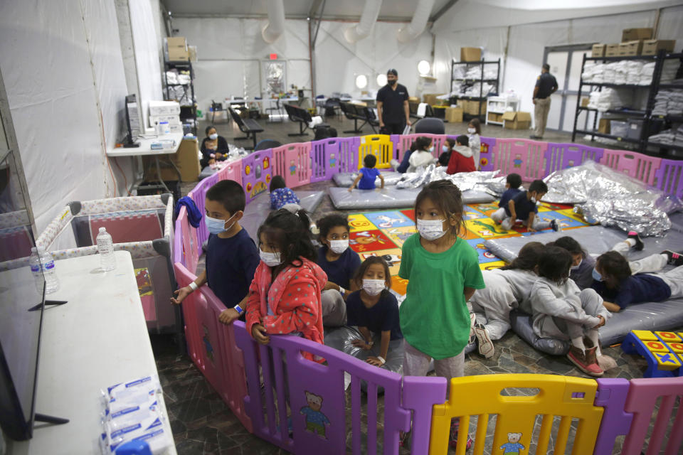FILE - Unaccompanied migrant minors aged 3 to 9, watch a television monitor inside a playpen at the U.S. Customs and Border Protection facility, the main detention center for unaccompanied children in the Rio Grande Valley, in Donna, Texas, on March 30, 2021. Stalled negotiations for the U.S. government to pay families separated at the border during Donald Trump's presidency have brought new threats of extortion. While specific reports are isolated, widespread extortion in Central America explains why many seek asylum in the United States in the first place and some advocates fear prospects of a large payment will fuel many more threats. It is far from clear whether families will receive any money at all from the U.S. government. (AP Photo/Dario Lopez-Mills, Pool, File)