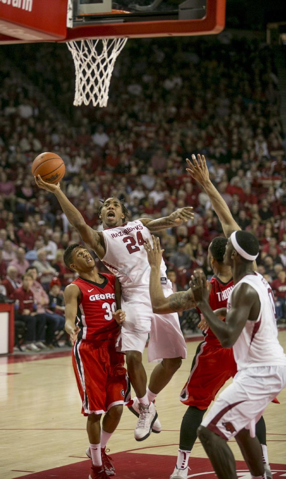 Arkansas guard Michael Qualls (24) leaps around Georgia guard J.J. Frazier (30) during the second half of an NCAA college basketball game on Saturday, March 1, 2014, in Fayetteville, Ark. Arkansas defeated 87-75. (AP Photo/Gareth Patterson)