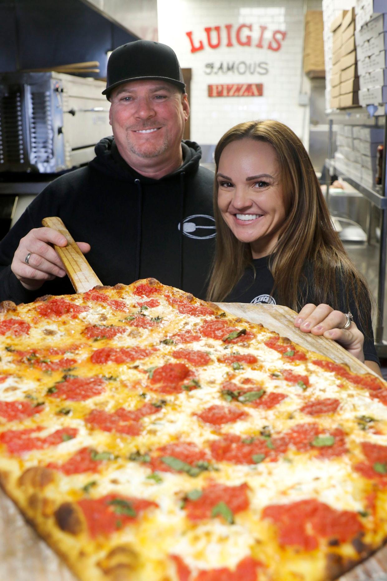 Luigi's Famous Pizza owners Kelly and Jason Emerson are shown with one of their signature rectangular pies at the Lincroft restaurant.