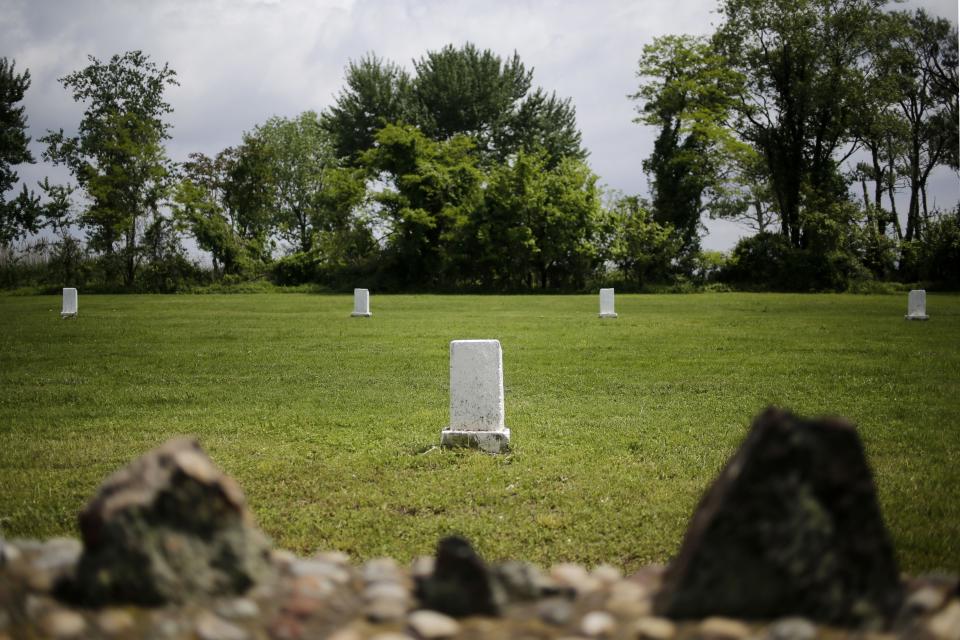 FILE - In this May 23, 2018, file photo, white markers, each indicating a mass grave of 150 people, are displayed on Hart Island in New York. The island has served as New York City's potter's field for 150 years, where part of the graveyard along the island's shoreline is gradually washing away. (AP Photo/Seth Wenig, File)