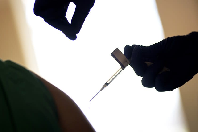 A health care worker is vaccinated with the Pfizer-BioNTech COVID-19 vaccine in Providence, R.I.