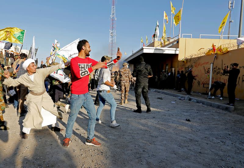 Protesters and militia fighters throw stones towards the U.S. Embassy during a protest to condemn air strikes on bases belonging to Hashd al-Shaabi (paramilitary forces), in Baghdad