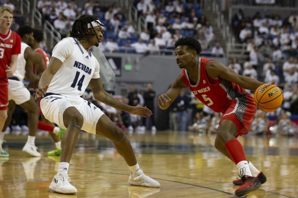 New Mexico guard Jamal Mashburn Jr. (5) drives past Nevada forward Tre Coleman (14) during the first half of an NCAA college basketball game in Reno, Nev., Monday, Jan. 23, 2023. (AP Photo/Tom R. Smedes)