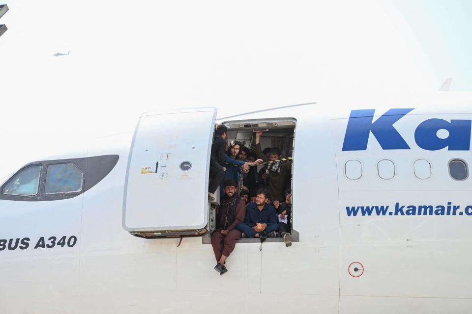 Afghan people climb up on a plane and sit by the door as they wait at the Kabul airport in Kabul on August 16, 2021. (Wakil Kohsar /AFP via Getty Images)