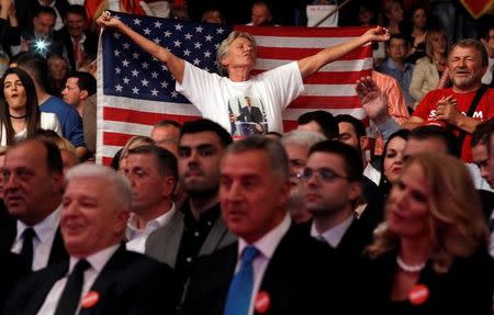 A supporter wearing a T-shirt with an image of Montenegrian PM Milo Djukanovic holds a U.S. flag during rulling Democratic Party of Socialist rally in Podgorica, Montenegro, October 14, 2016. REUTERS/Stevo Vasiljevic