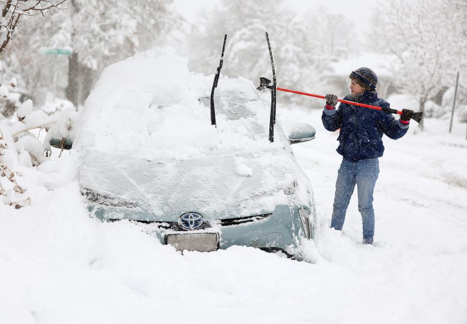 Cathy Morgan-Mace cleans snow and ice off her family's car during a snowstorm in Salt Lake City, Utah, on Wednesday (Kristin Murphy/The Deseret News via AP)