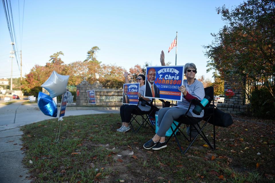 Ashleigh Neville (left) and Dawn Clay (right) wave signs outside of Julian Smith Casino as the sun rises on Tuesday, Nov. 8, 2022. 