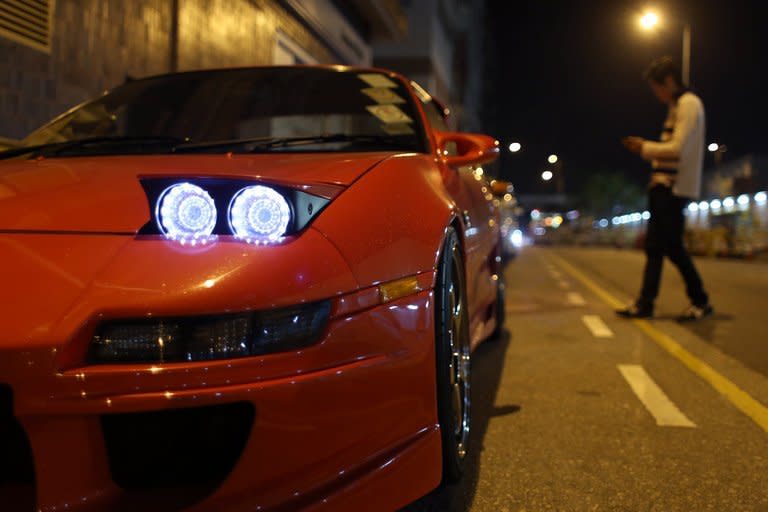 A man walks past modified racing cars before a race in the early hours of the morning in Hong Kong, on April 7, 2013. As night begins to give way to dawn, 40 high-performance cars pull up on an empty Hong Kong backstreet. Their revving engines fill the air with a heavy smell of petrol as the city sleeps