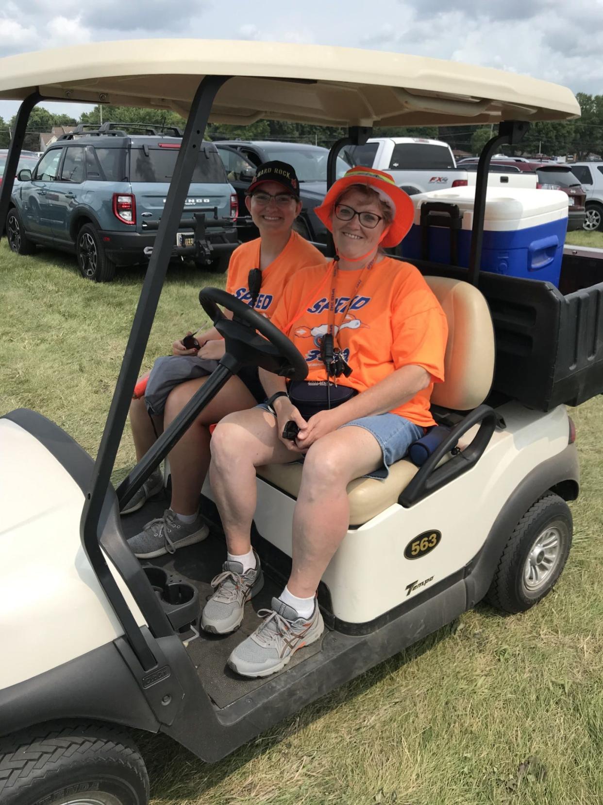 Julie Cunningham of Lambertville and her daughter, Monica, use a golf cart Tuesday to oversee parking in the large parking lot off M-50 at the Monroe County Fairgrounds. Monica is a senior on the Bedford High School Robotics Team, which is handling parking for the fair.