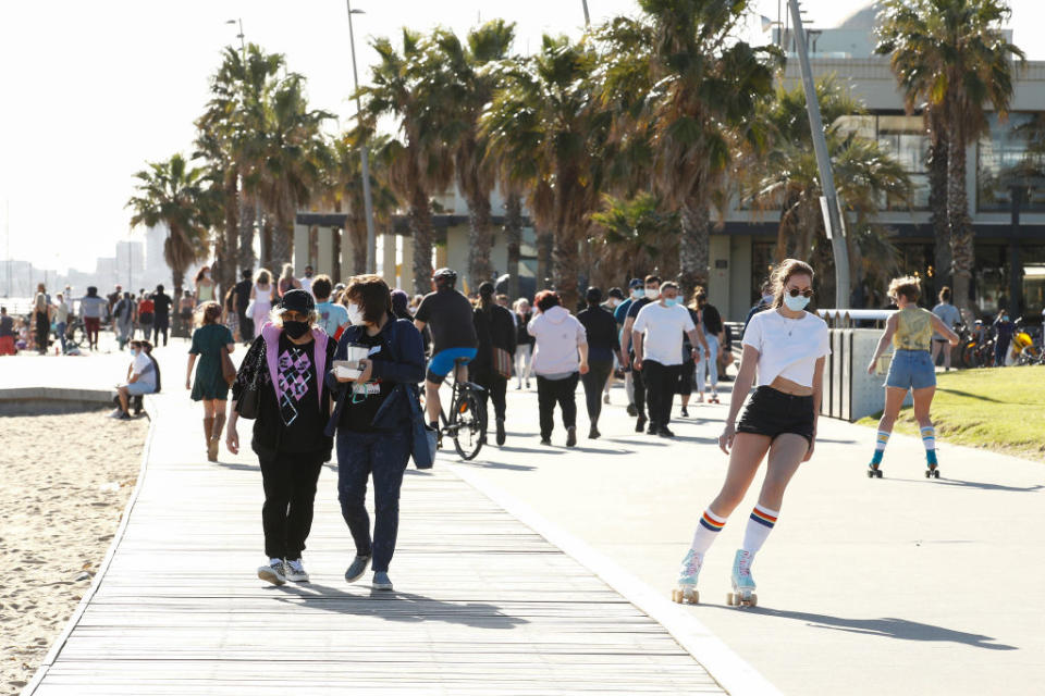 A photo of people in Melbourne enjoying the sunshine, with some wearing face masks.