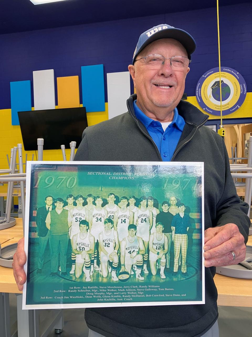 Steve Galloway poses with a replica photo of the 1970-71 Maysville boys basketball team that reached the Class AA state tournament. Galloway was the point guard on the team, which made the first state tournament in school history that season. They are among many former players that have embraced the current team's run to the state tournament