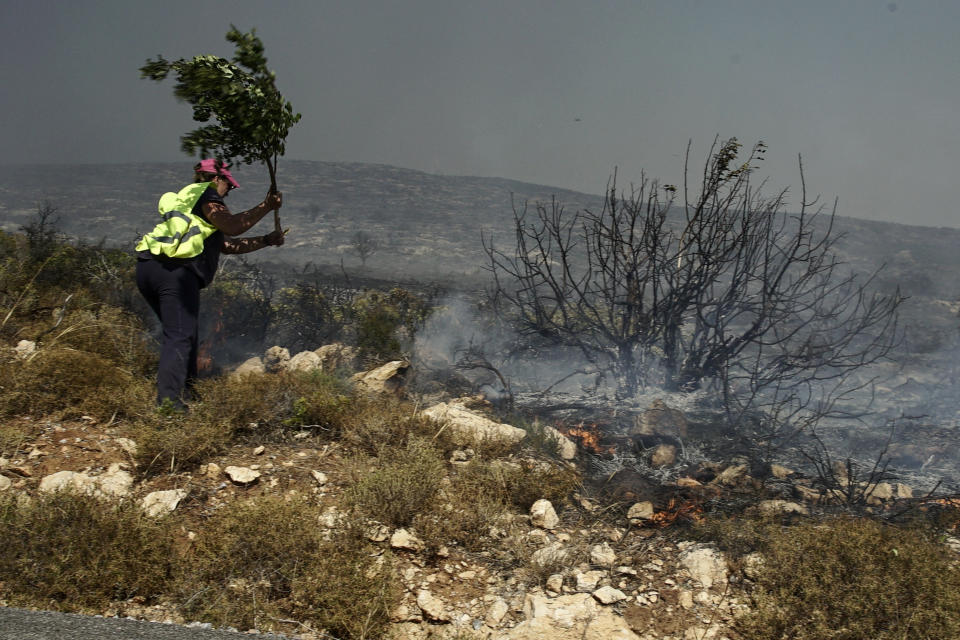 A municipal worker extinguishes a wildfire at Elafonisos island, south of Peloponnese peninsula, on Saturday, Aug. 10, 2019. A wildfire which broke out on Elafonisos island in southern Greece on Saturday has prompted the evacuation of a hotel and camping as a precautionary measure, with no injuries reported, according to Greek national news agency AMNA. (AP Photo/Nikolia Apostolou)