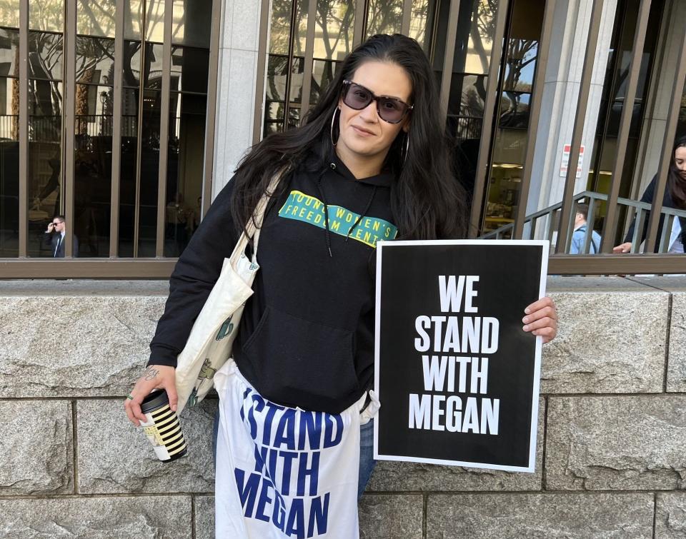 A person holds a sign reading "we stand with megan"