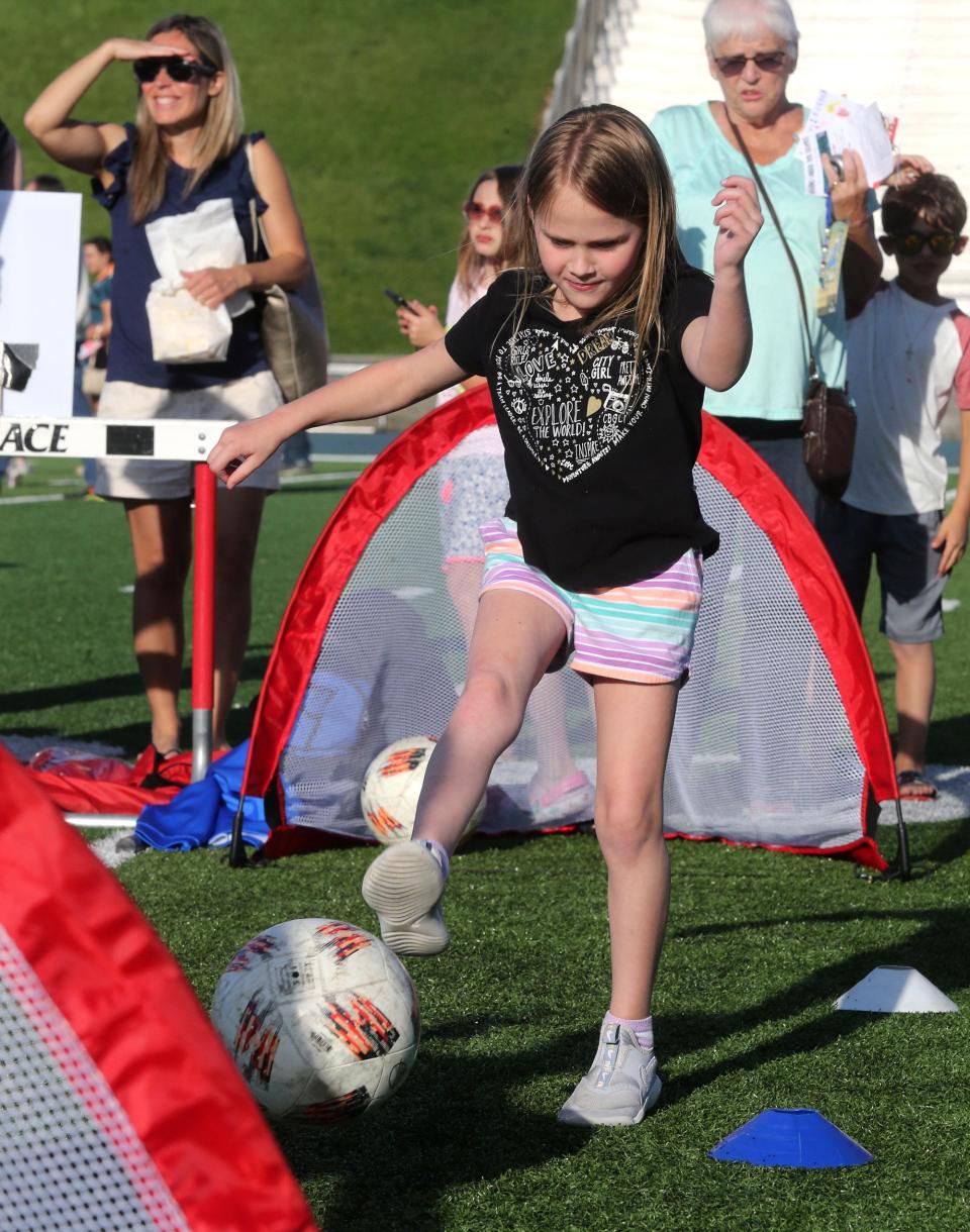 Remi Pearson kicks a ball in the Lake Youth Athletics booth on May 9 during Reading Under the Lights at Blue Streak Stadium in Lake Township. The event promoted reading and took place on the football field.